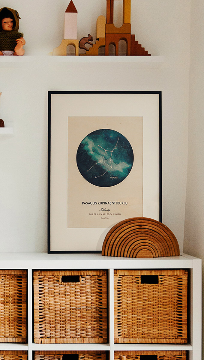 A cozy children's room corner with a white cabinet topped with a wicker basket, a globe, and animal figurines. Above the cabinet is a large framed print from a graphic design project for client Cozywood